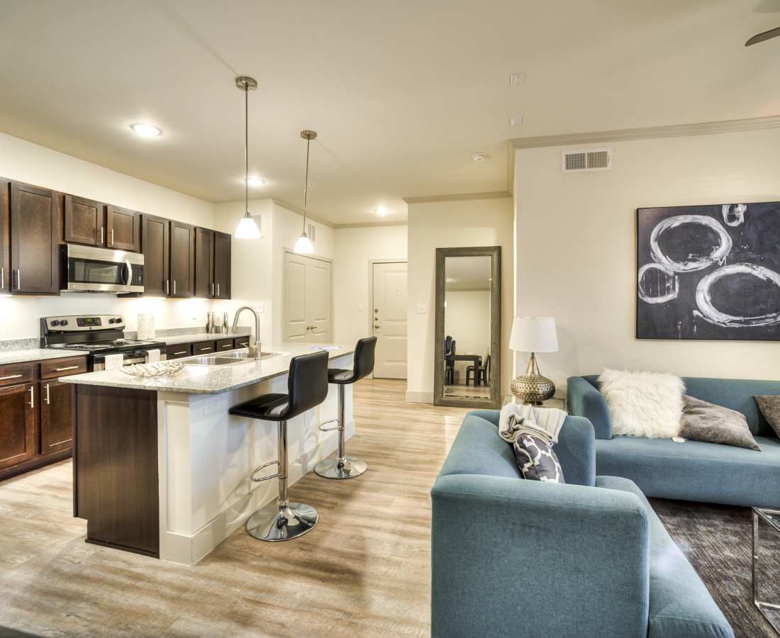 Modern kitchen with granite countertops, stainless steel appliances, and island seating in open layout apartment at Magnolia Park Apartments in Houston, Texas