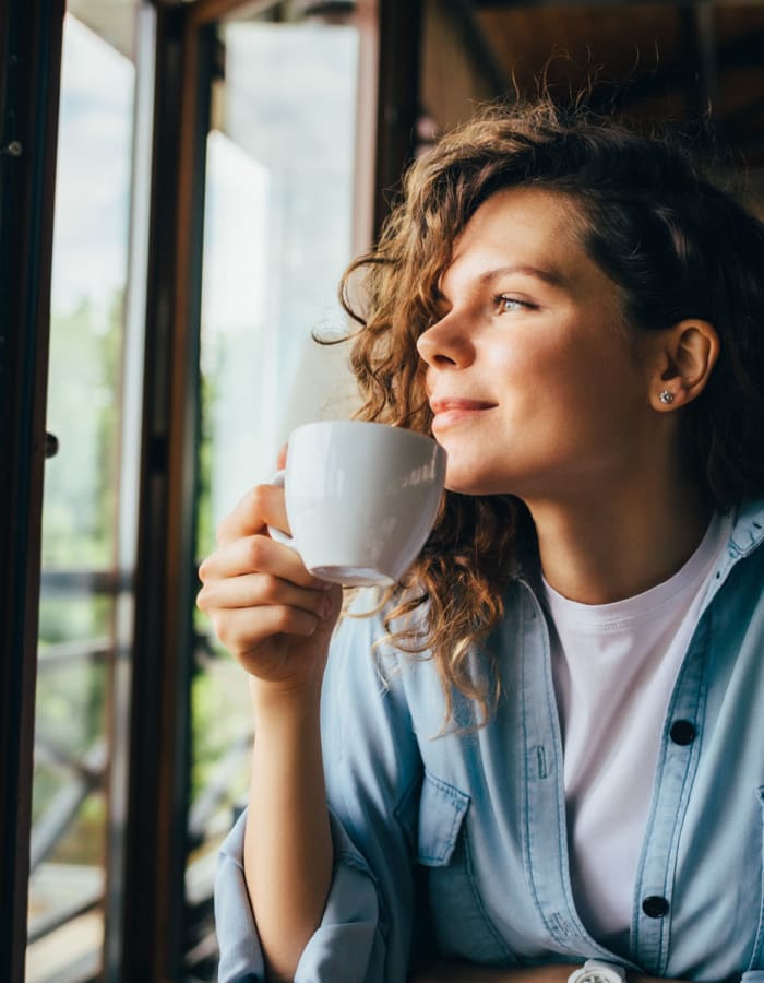 Student savoring a cup of coffee at a cafe near The Gramercy in Manhattan, Kansas