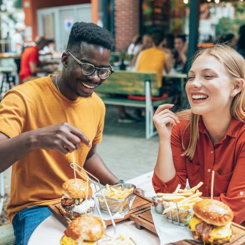 Enjoying burgers and fries at a bustling outdoor café at Messina Luxury Apartments in New Smyrna Beach, Florida