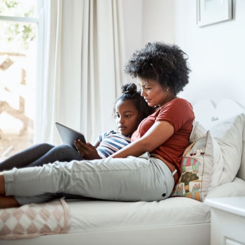 A mother and daughter looking at a tablet in a bedroom at The Village at Whitehurst Farm in Norfolk, Virginia