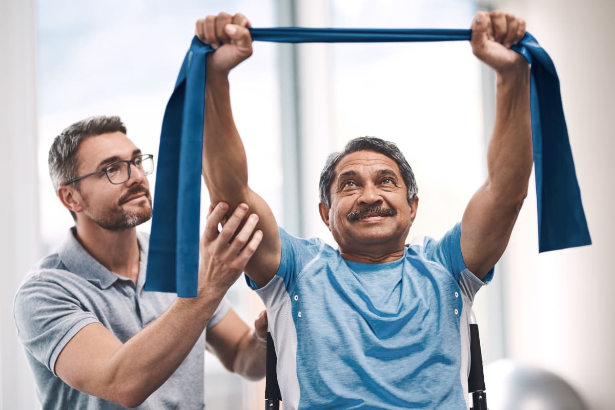 Resident Using stretch bands with assistant supporting arms