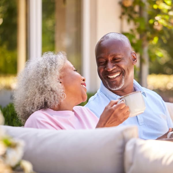 Resident outdoors smiling while embracing her daughter at Pacifica Senior Living San Leandro in San Leandro, California.