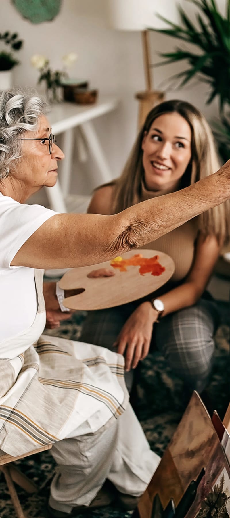 Resident painting with a caretaker providing assistance at a WISH community