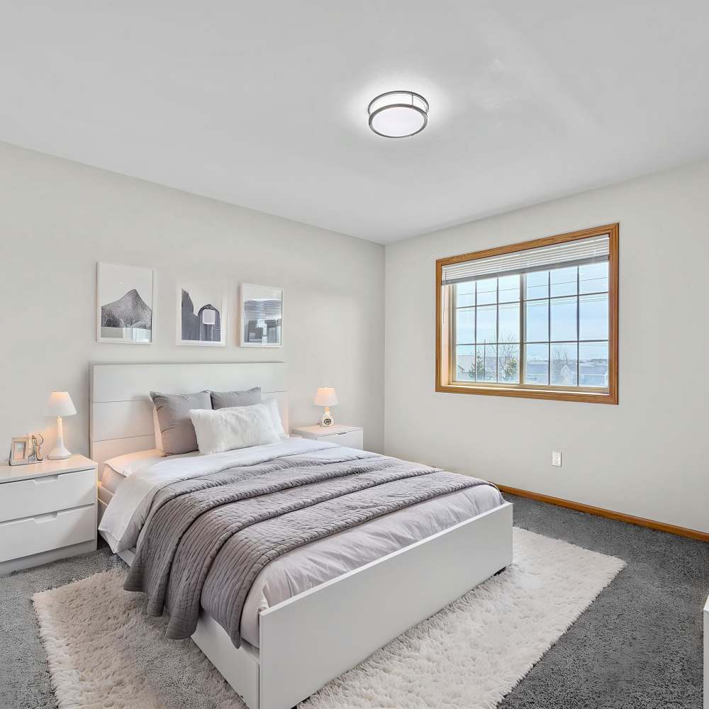 Modern bedroom with queen size bed, large window and carpet flooring at Prairie Bend in Cedar Rapids, Iowa