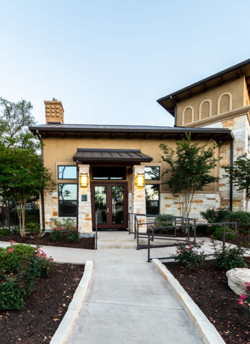 Well manicured clubhouse entrance lined with flowers and plants of Marquis at Barton Trails in Austin, Texas