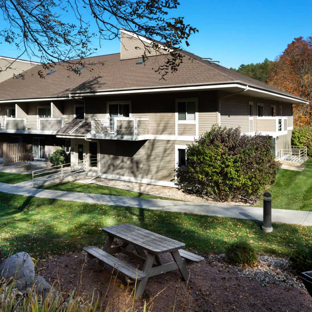 Modern multifamily building with lush greenery and picnic area at Cedar Glen Apartments in Cross Plains, Wisconsin