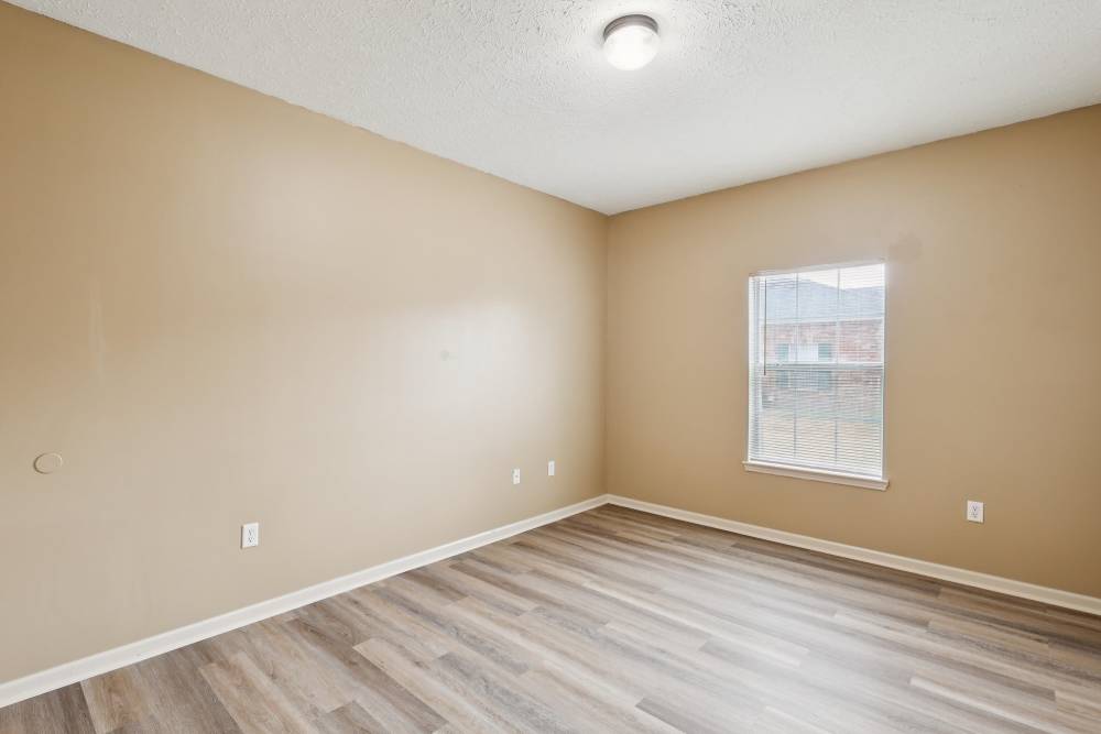 Unfurnished bedroom with wood-style flooring and large window at Camden Park in Canton, Mississippi