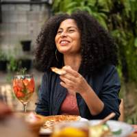 Woman enjoying meal with friends at outdoor table near Sagamore Apartments in Benbrook, Texas