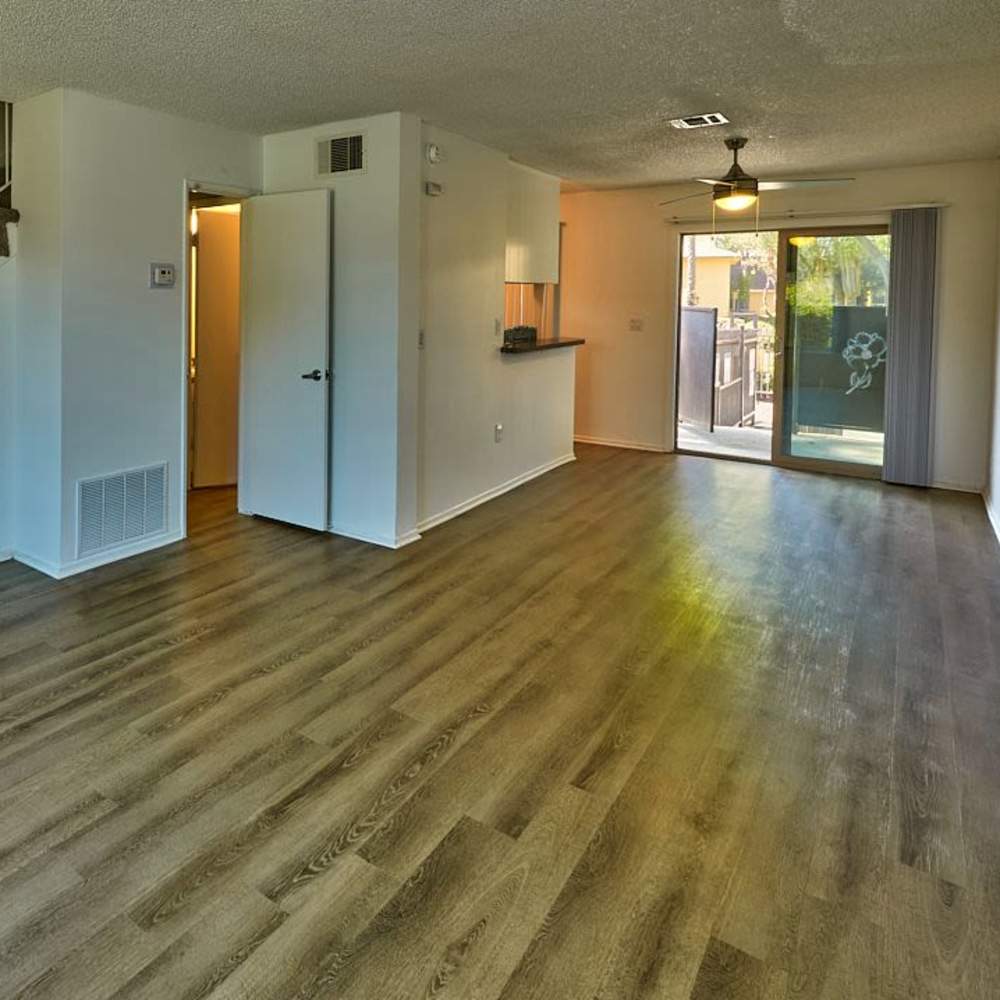 Unfurnished living room with wood-style flooring and ceiling fan at Las Lomas Gardens in La Habra, California