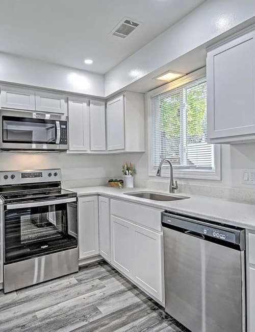 Modern kitchen with granite countertops, wooden cabinets, dishwasher and stainless-steel appliances at Woodside Village in Valparaiso, Indiana
