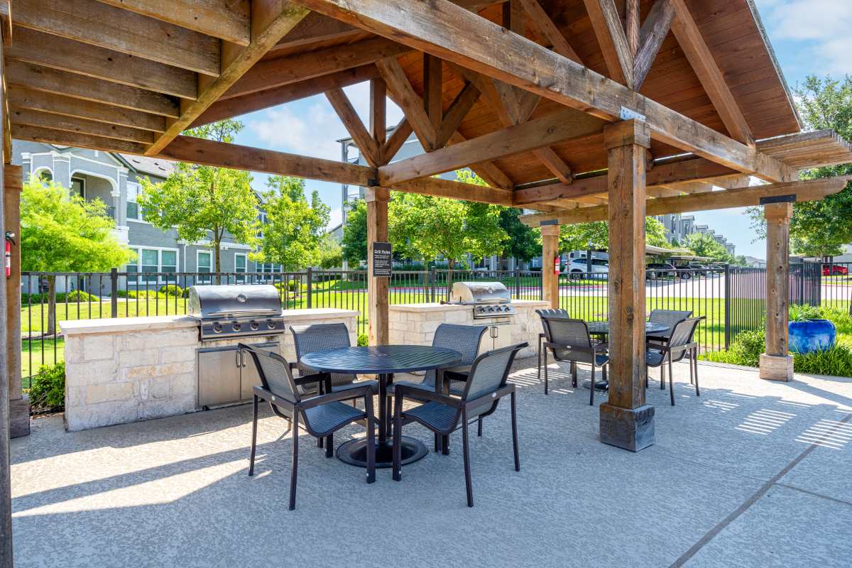 Outdoor barbeque area with seating at Travesia Apartments in Austin, Texas