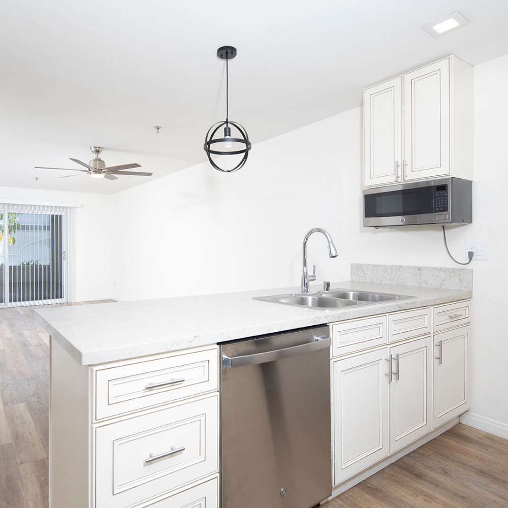 Modern kitchen with white cabinetry, island and stainless-steel appliances at Hillcrest Summit in San Diego, California