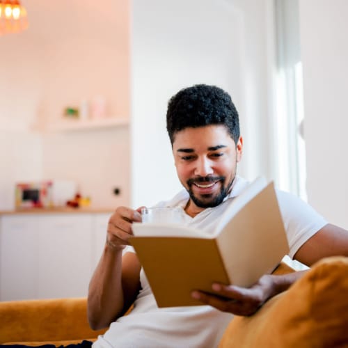 Resident reading a book on the couch while enjoying some tea at Bristol House in Washington, District of Columbia