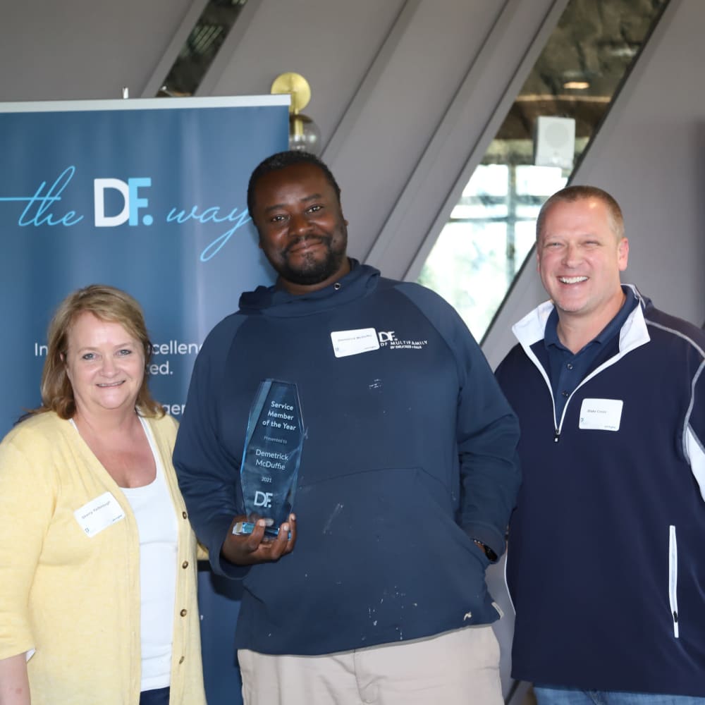 Three employees holding an award at Drucker + Falk in Newport News, Virginia