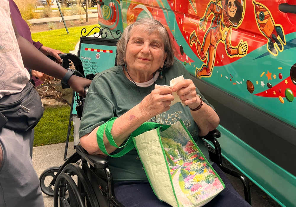 Resident smiling next to an ice cream truck at Merrill Gardens at The University in Seattle, Washington