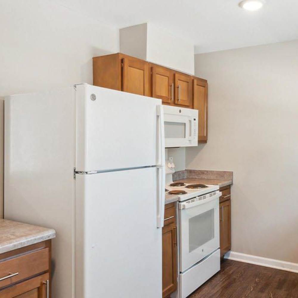 Modern kitchen with stainless steel appliances, granite countertops, and wood-style flooring at Winston Commons in Pontiac, Michigan