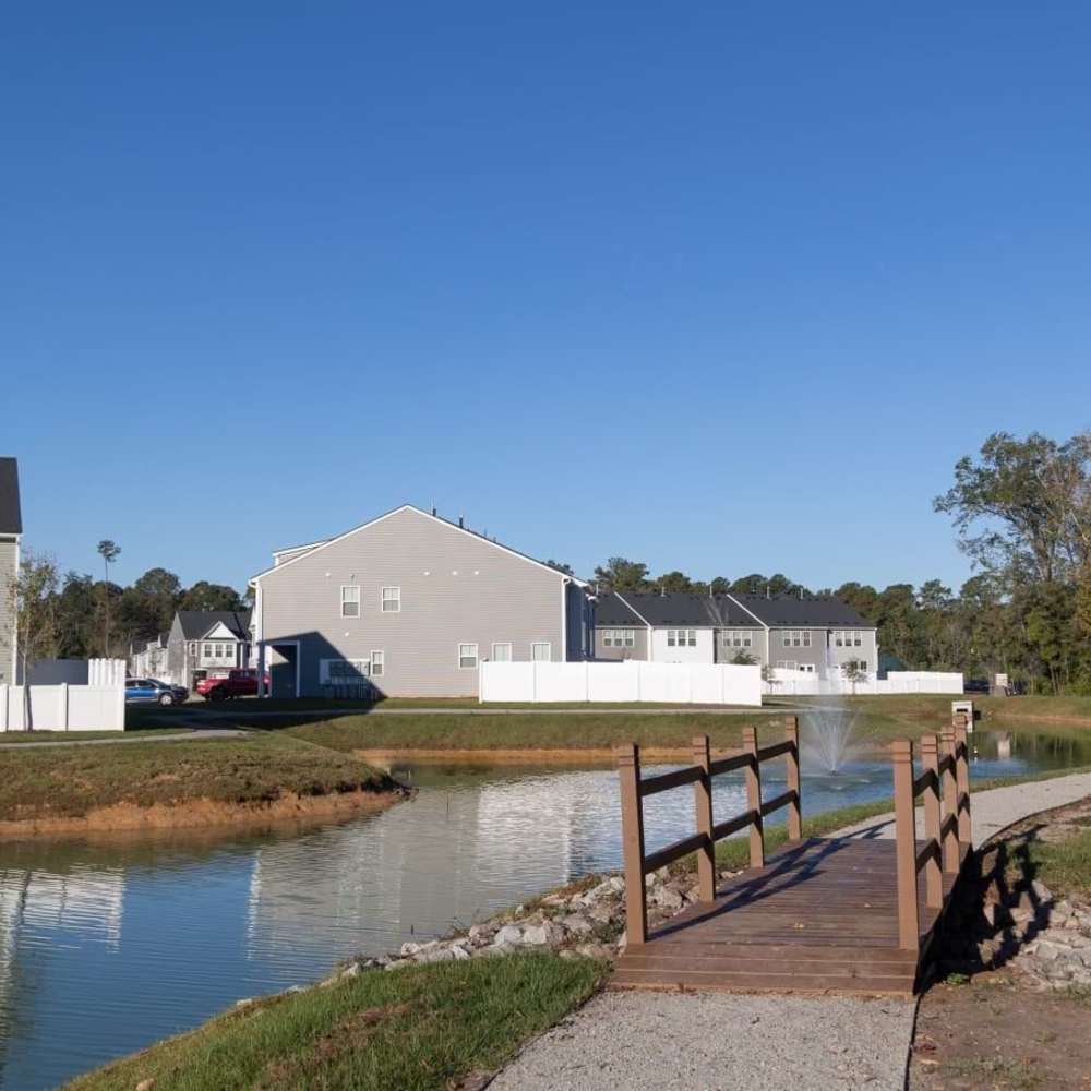 Walking path with a wooden bridge beside a pond and nearby homes at Chamberlain Pines in Summerville, South Carolina