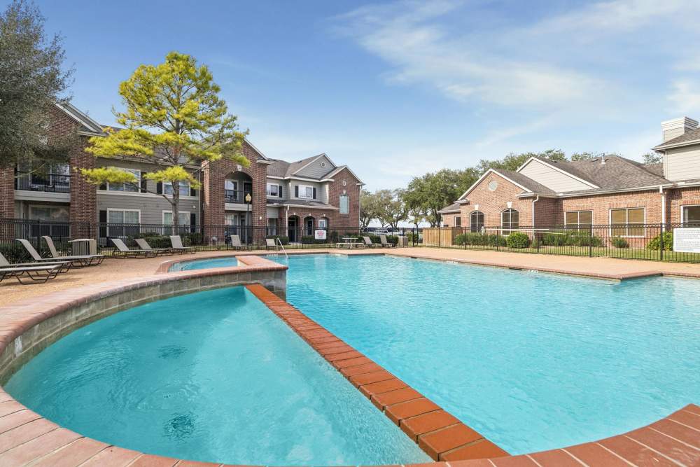 Swimming pool with lounge chairs at Bristol Apartments in Houston, Texas