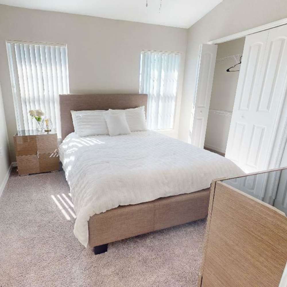 Cozy bedroom with plush carpet, large windows, and stylish furnishings at The Reserve at Brookhaven in Palm Coast, Florida