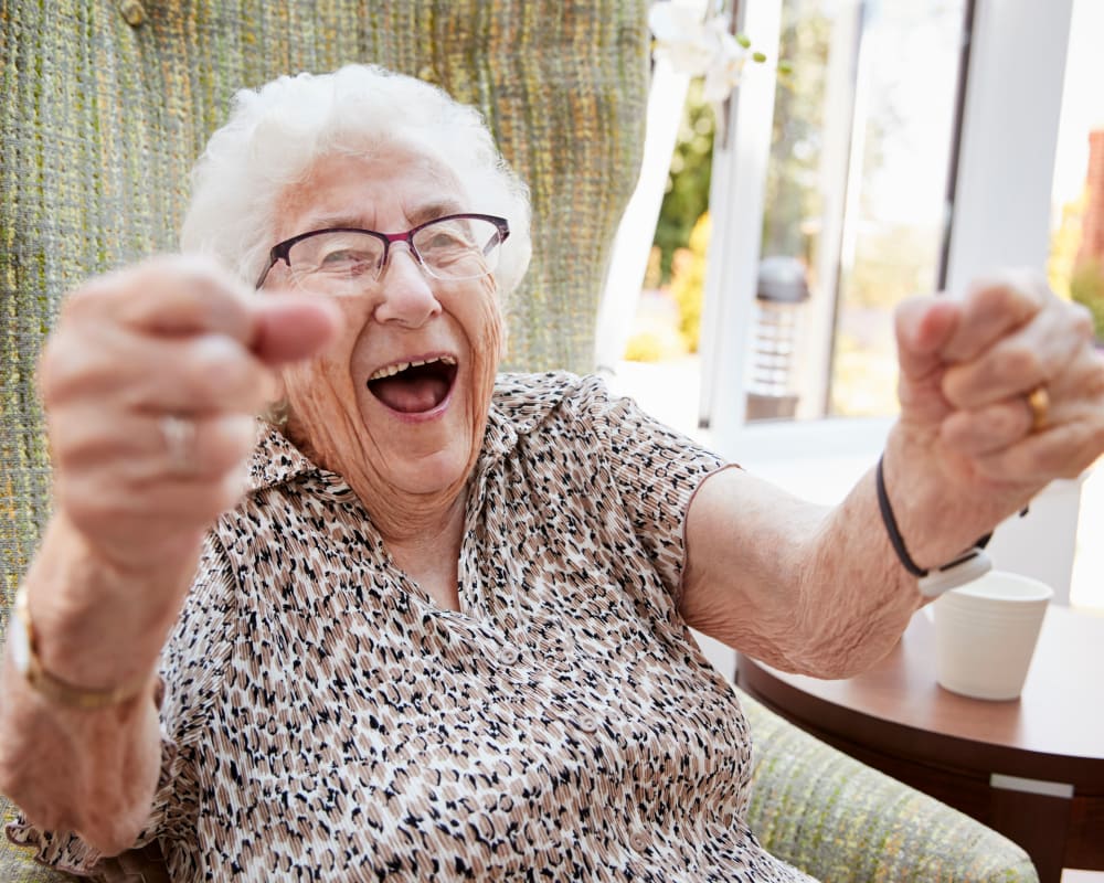 Resident in a chair reaching upwards and smiling at Parker Place in Parkersburg, Iowa.