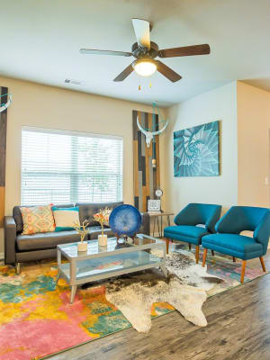 Eclectically decorated model living room with a ceiling fan and wood-style floors at Creekside at Kenney's Fort in Round Rock, Texas