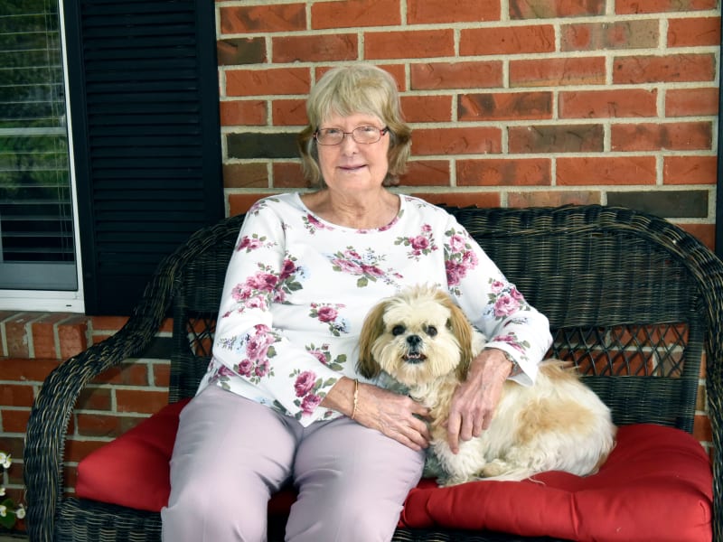 Resident with her small dog sitting on the patio at Garden Place Millstadt in Millstadt, Illinois