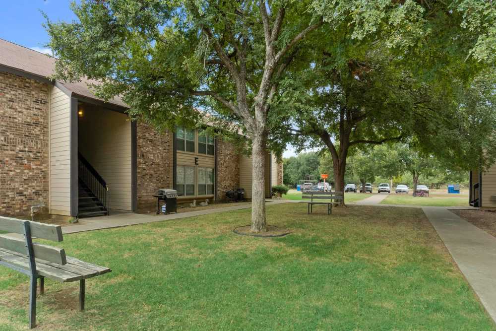 Exterior view of the apartments with park chair and walk ways at Woodland Village Apartments in Breckenridge,  Texas