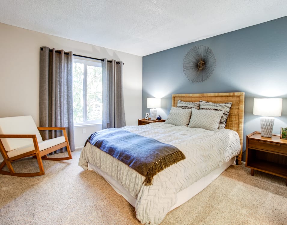 Well-furnished master bedroom with an accent wall and draped windows in a model home at Waterstone Fremont in Fremont, California