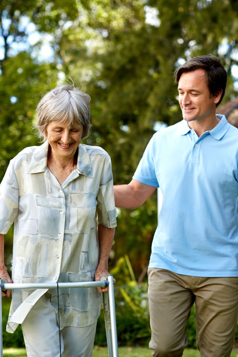 Caregiver and resident using a walker enjoying a walk outside at Trustwell Living at Mission Springs in Mission, Kansas