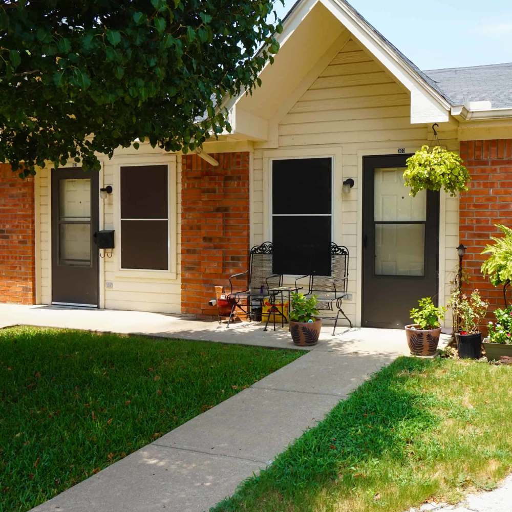 Charming entryway with lush plants and inviting seating area at The Parc at Bakers Pointe in Richland Hills, Texas
