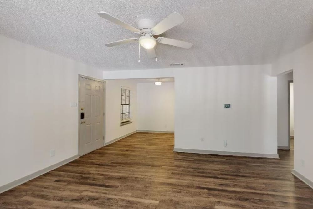 Wood-style flooring and a ceiling fan in an apartment living room at The Haylie in Garland, Texas
