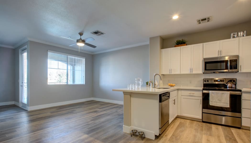 Kitchen and living area with ceiling fan in open-concept floor plan of model home at Waterford at Peoria in Peoria, Arizona