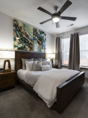 Elegant model master bedroom with plush carpeting and a ceiling fan at Steelyard in Oklahoma City, Oklahoma