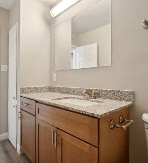 Modern bathroom with granite vanity, mirror, toilet at Charleston Square Apartments in Columbus, Indiana