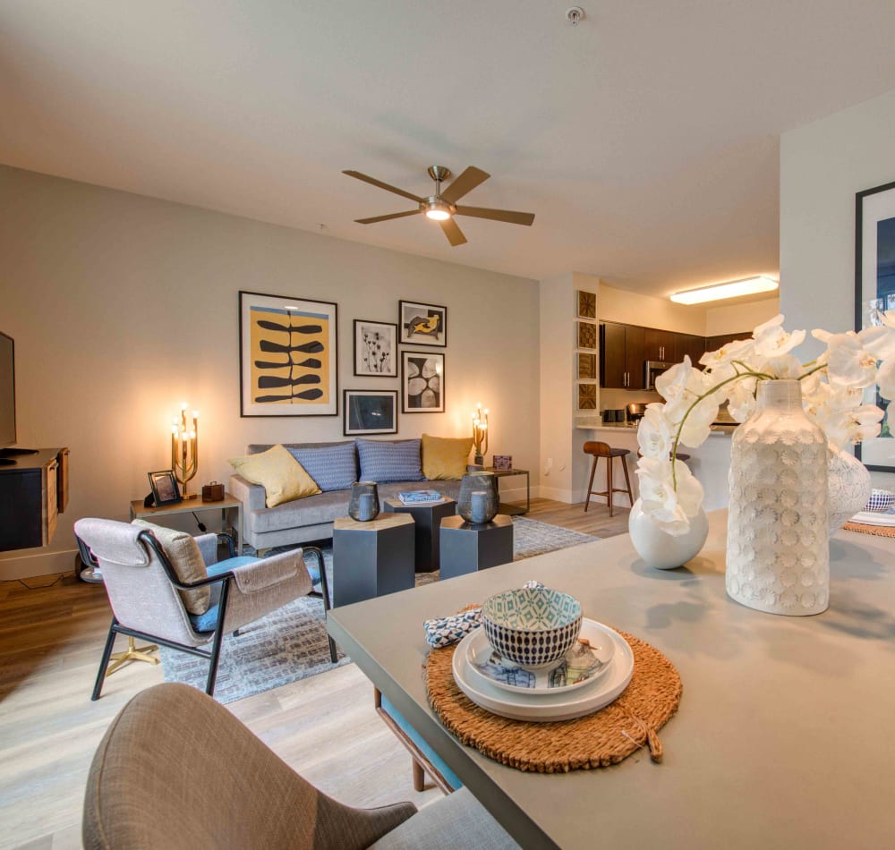 Well-furnished living area with large bay windows and plush carpeting in a model home at Sofi Warner Center in Woodland Hills, California