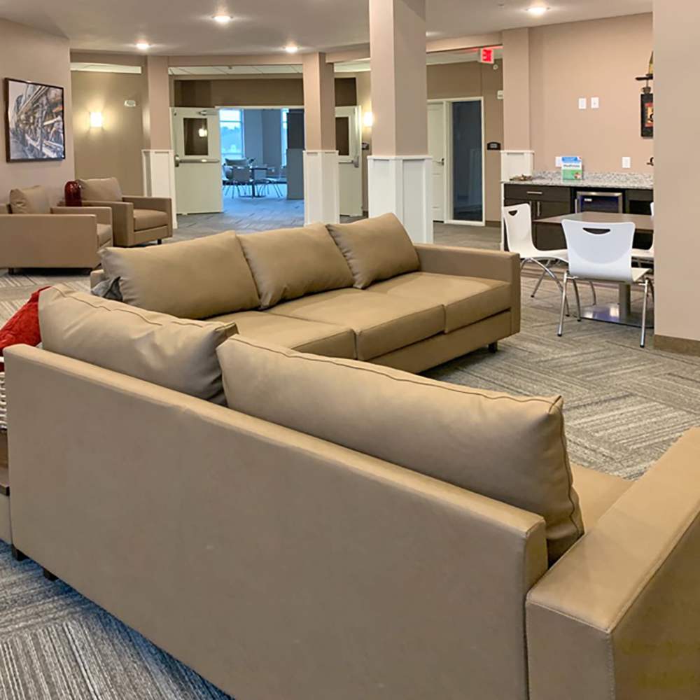 Community clubhouse with large couch and carpet flooring at Depot on Main in Zimmerman, Minnesota