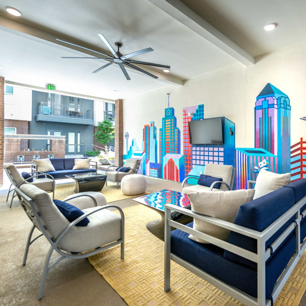 Outdoor covered patio with vibrant Dallas skyline painting and seating at Hall Street Flats in Dallas, Texas