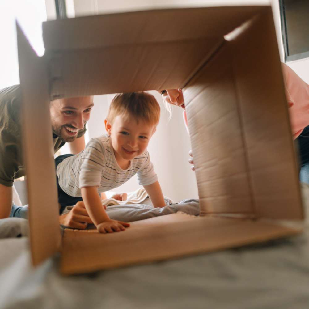 Child playing in a cardboard box with family members nearby at Cedar Glen Apartments in Cross Plains, Wisconsin
