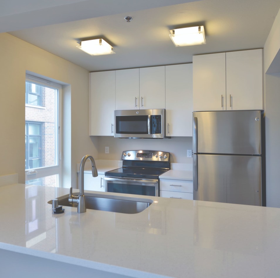 Modern kitchen with stainless-steel appliances in the open-concept floor plan of a model home at 2900 on First Apartments in Seattle, Washington