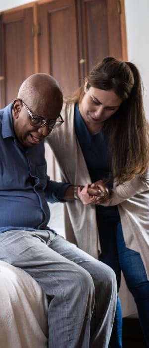 Resident being helped out of bed by a caretaker at a WISH community