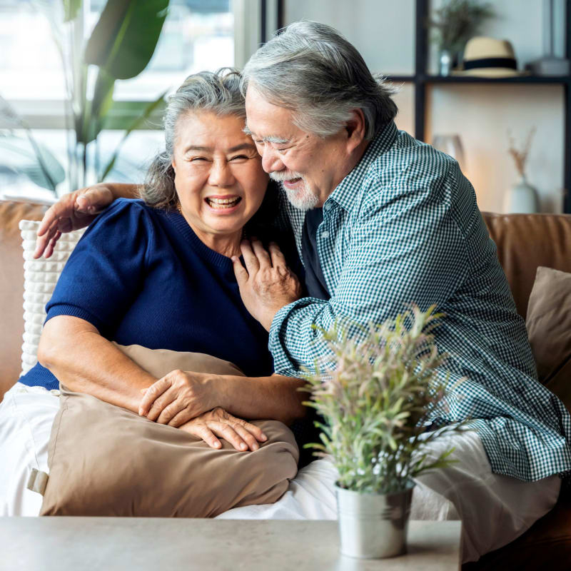 Older couple smiling on their couch at Attain at Towne Centre, Fredericksburg, Virginia