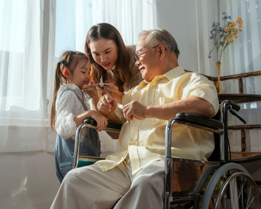 Resident in wheelchair spending time with his family at The Peaks at South Jordan Memory Care in South Jordan, Utah