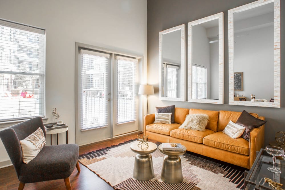 Full size couch, coffee tables, sitting chairs with large, tall mirrors on wall at Marq Midtown 205 in Charlotte, North Carolina