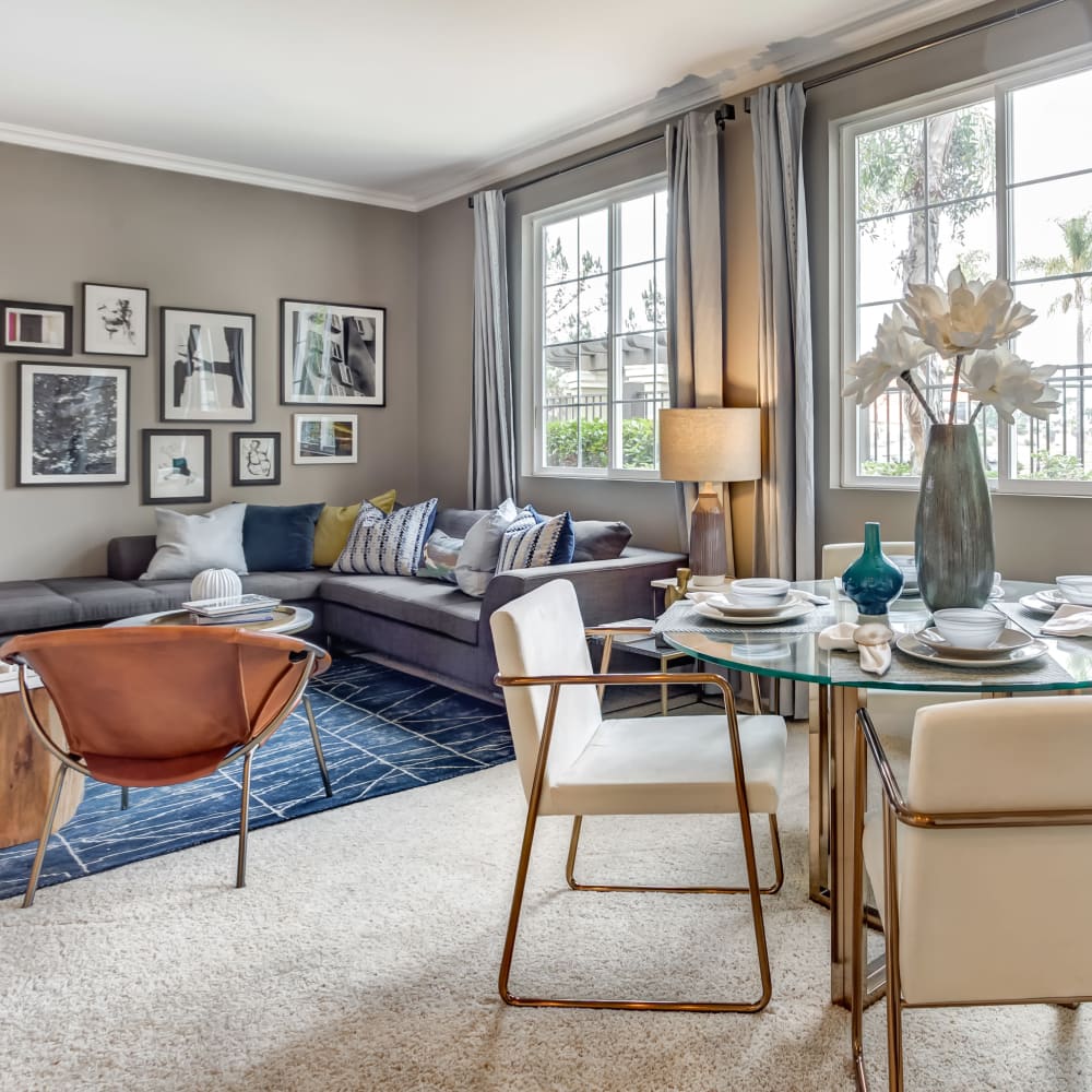 Open-concept living and dining areas with plush carpeting and accent walls in a model home at Sofi Highlands in San Diego, California