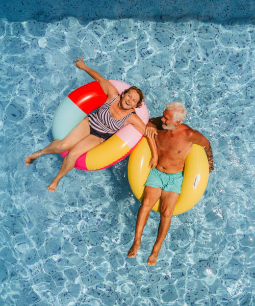 Senior couple relaxing on pool floats at Citation Club in Farmington Hills, Michigan