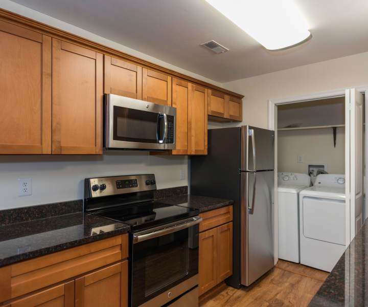 Stainless-steel appliances with wooden cabinets in the kitchen and the laundry facility at Fox Chase Apartments in Fredericksburg, Virginia