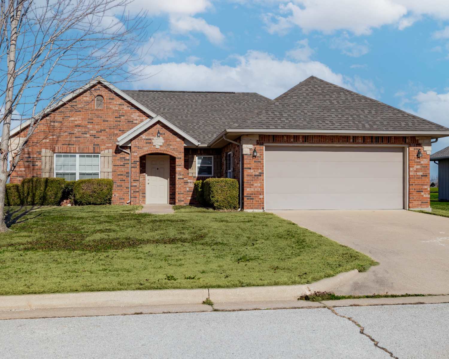 Charming brick home with lush landscaping and inviting curb appeal at Prairie Hill Estates II in Carl Junction, Missouri.