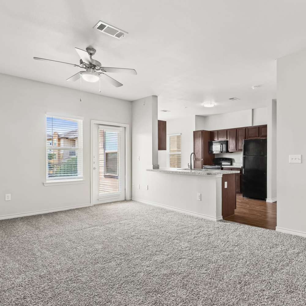 View of kitchen with black appliances from a carpeted, unfurnished living room at Sunset Lodge in Odessa, Texas