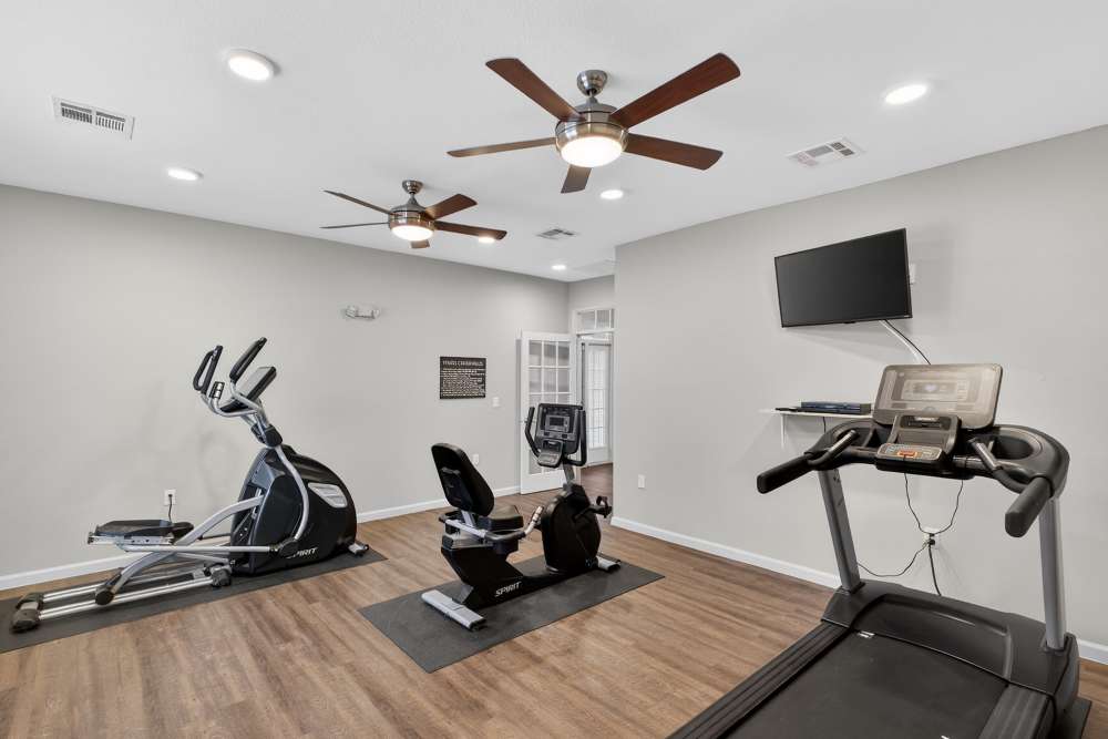 Modern fitness room featuring state-of-the-art equipment and elegant ceiling fans for a refreshing workout experience at Lakewood Crossing in Granbury, Texas. 