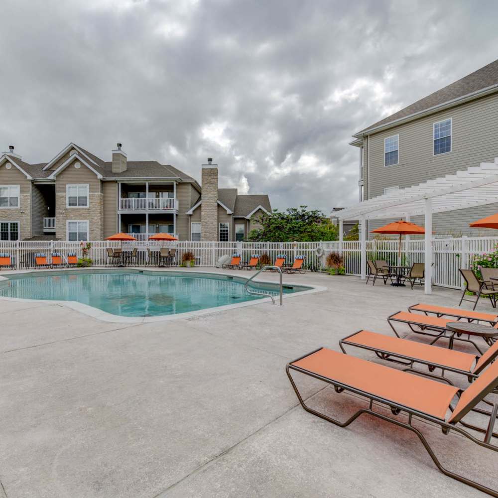 Charming poolside retreat with vibrant orange loungers and lush landscaping at Boulder Springs in Maryland Heights, Missouri